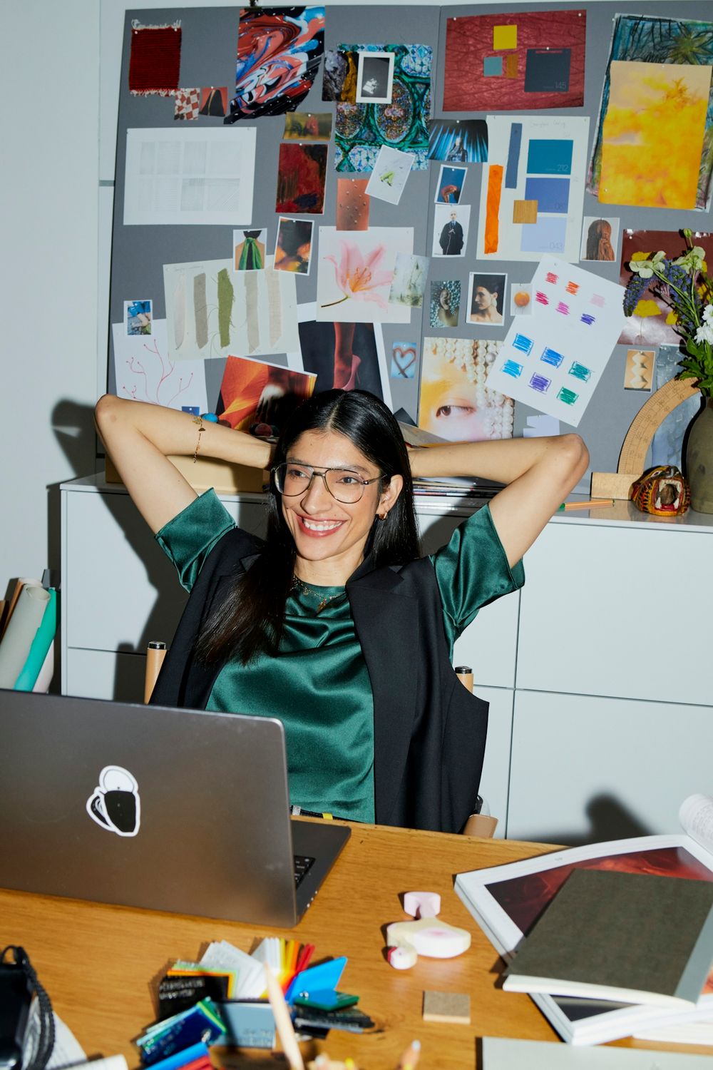 Designer at her desk in front of a moodboard wall